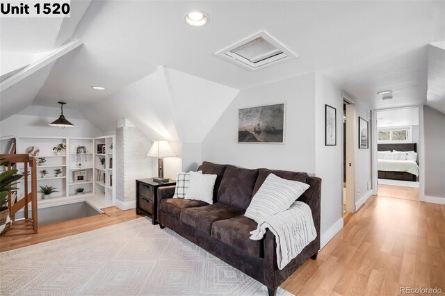 living room featuring recessed lighting, vaulted ceiling, light wood-style flooring, and attic access