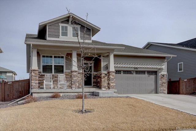 view of front of house featuring driveway, stone siding, a porch, fence, and a garage