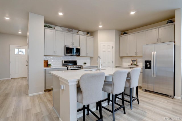 2785 Black Hawk Pl, Brighton, CO 80601 - kitchen with appliances with stainless steel finishes, a kitchen breakfast bar, a kitchen island with sink, backsplash, and recessed lighting