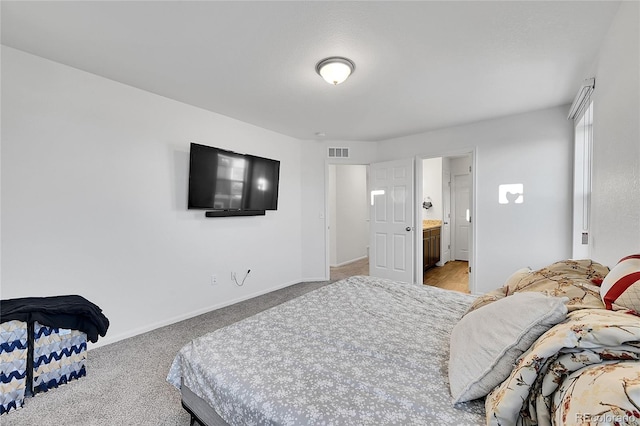 bedroom with connected bathroom and light carpet