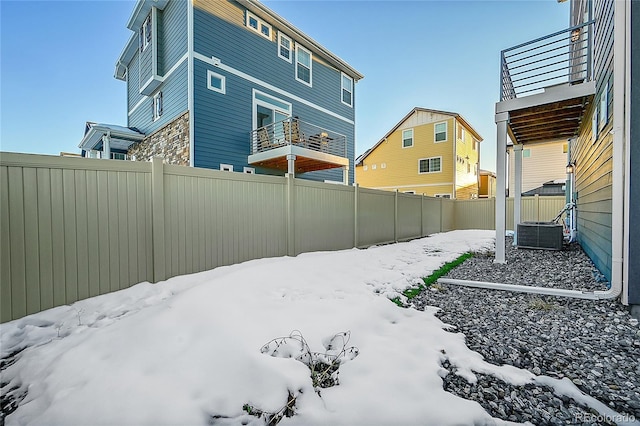 yard layered in snow with central AC and a balcony