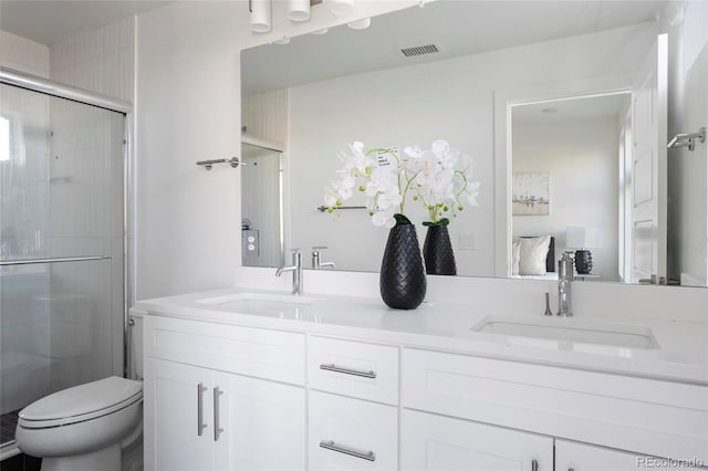 bathroom featuring a shower with door, vanity, and toilet