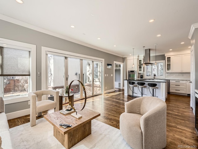 living area with dark wood-style floors, baseboards, ornamental molding, and recessed lighting