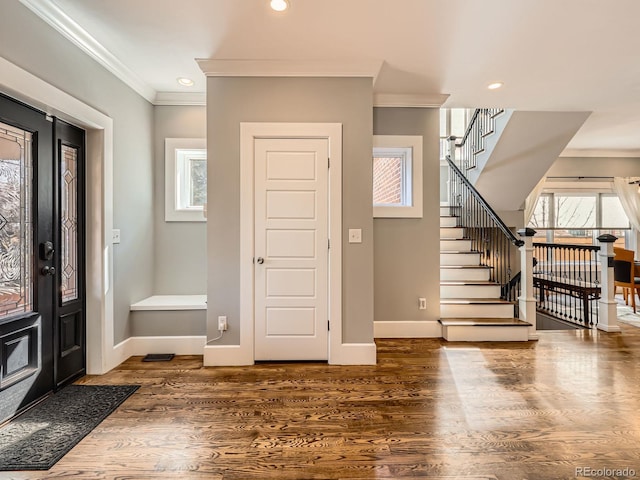 entryway with stairway, crown molding, baseboards, and wood finished floors