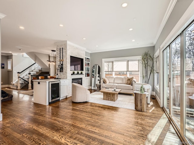 living room with beverage cooler, crown molding, dark wood-style flooring, and stairs