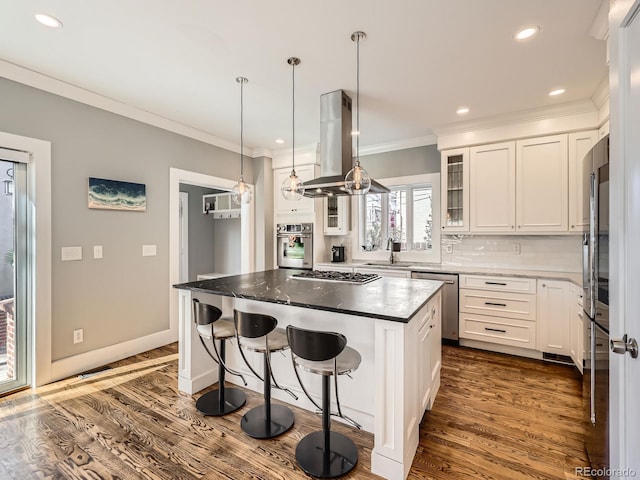 kitchen with dark wood-style flooring, crown molding, appliances with stainless steel finishes, white cabinetry, and island range hood