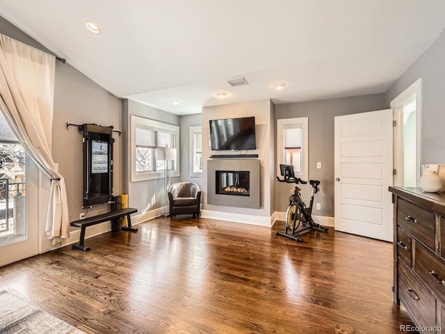 living area with a glass covered fireplace, recessed lighting, baseboards, and wood finished floors