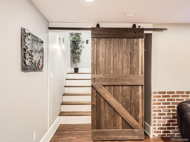 interior space with a barn door, wood finished floors, and baseboards