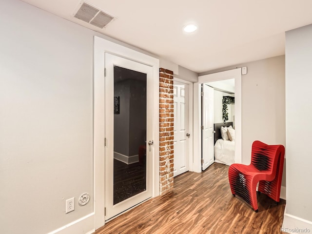 corridor featuring baseboards, visible vents, and wood finished floors