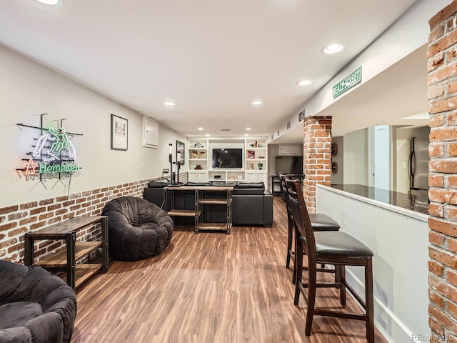 living room with ornate columns, brick wall, wood finished floors, and recessed lighting