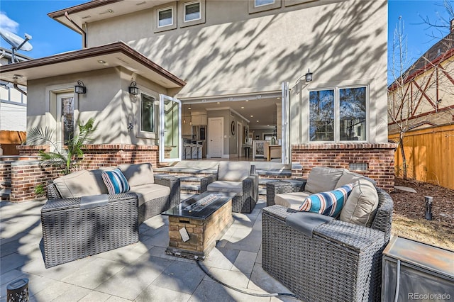 view of patio with an outdoor living space with a fire pit and fence