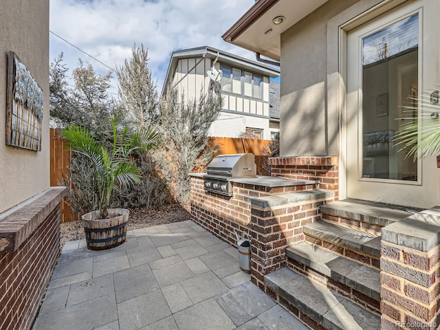 view of patio with fence, grilling area, and an outdoor kitchen