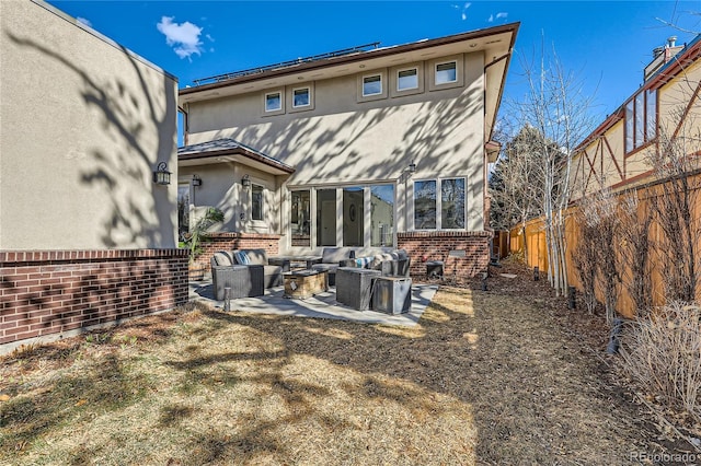 rear view of property with a patio, brick siding, fence, an outdoor living space, and stucco siding