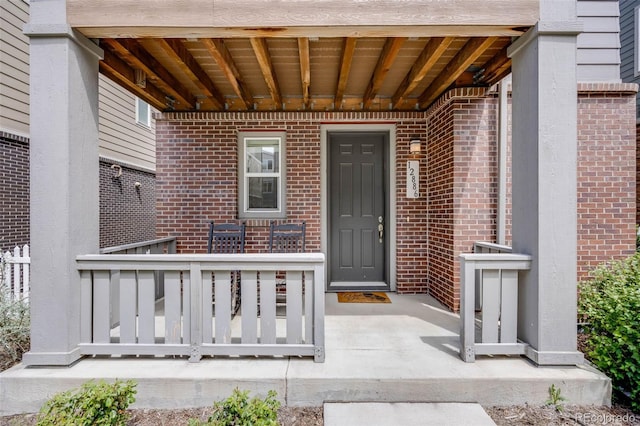 property entrance featuring brick siding and a porch