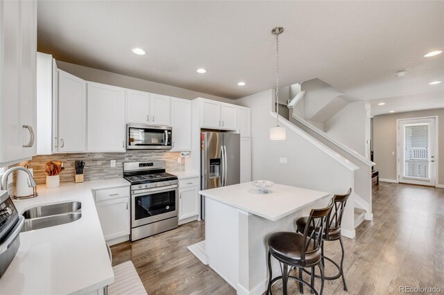 kitchen with appliances with stainless steel finishes, tasteful backsplash, a center island, a breakfast bar, and a sink