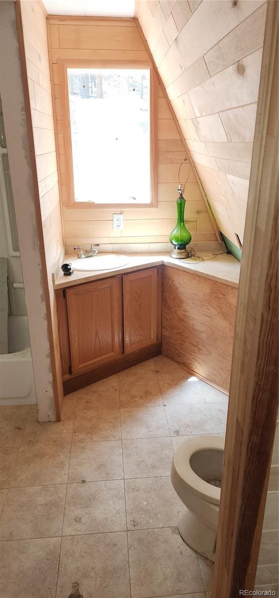1 Ute Trl, Evergreen, CO 80439 - full bath featuring lofted ceiling, wood walls, vanity, and tile patterned floors
