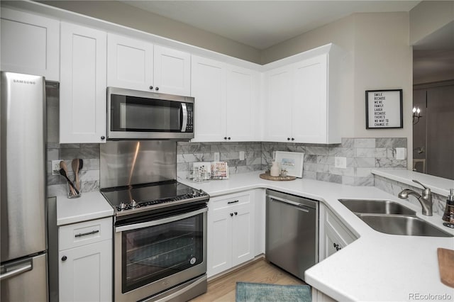 kitchen with sink, tasteful backsplash, light hardwood / wood-style floors, white cabinets, and appliances with stainless steel finishes