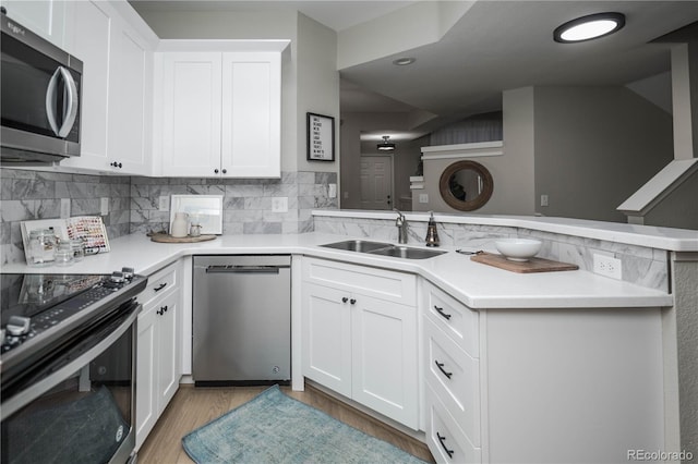 kitchen with kitchen peninsula, white cabinetry, sink, and stainless steel appliances