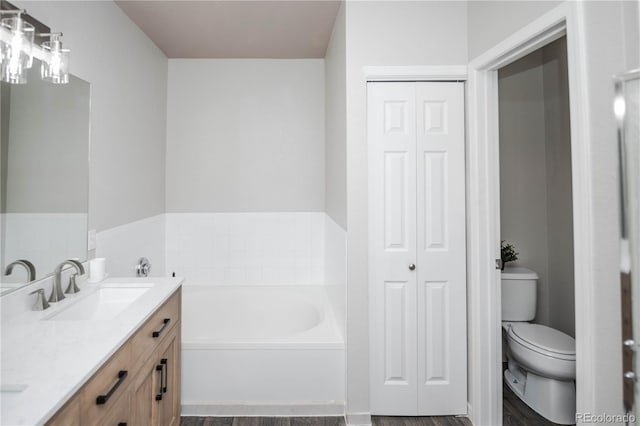 bathroom with a washtub, wood-type flooring, vanity, and toilet