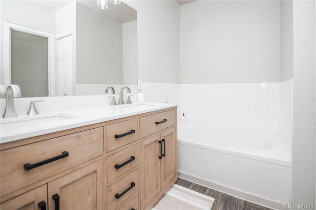 bathroom with a bath, vanity, and wood-type flooring