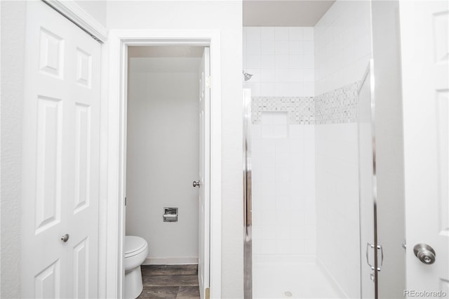 bathroom featuring walk in shower, hardwood / wood-style floors, and toilet