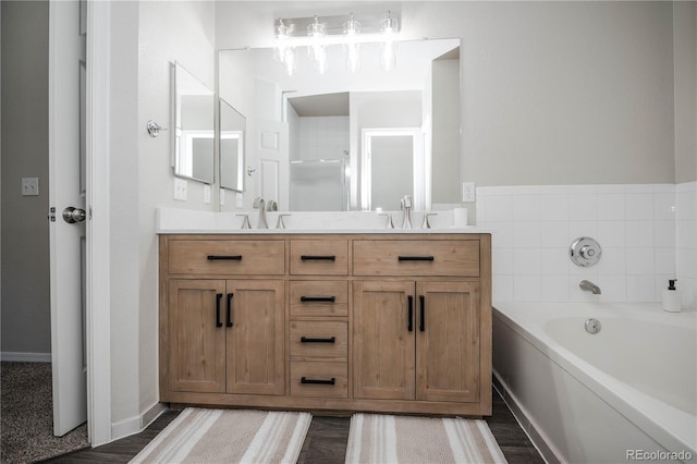 bathroom with a bath, vanity, and hardwood / wood-style floors