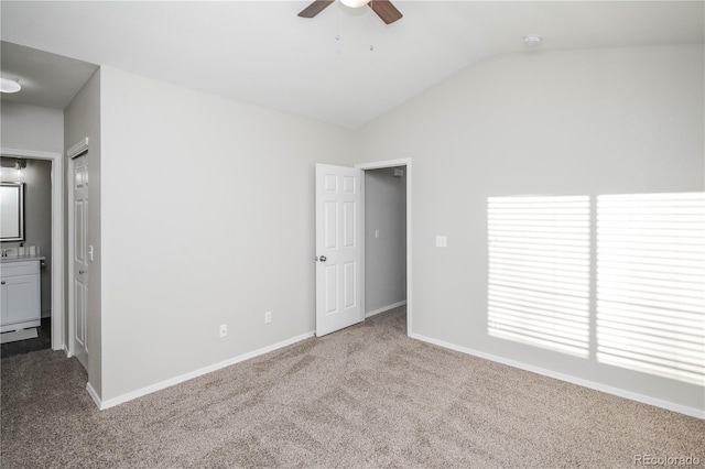 unfurnished bedroom featuring carpet flooring, ceiling fan, ensuite bathroom, and vaulted ceiling