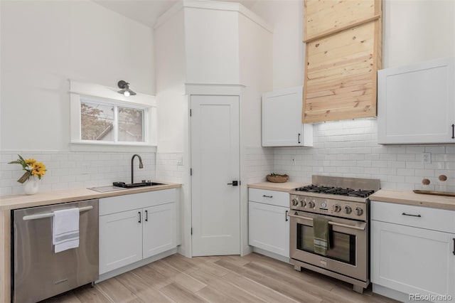 kitchen featuring white cabinets, light wood-type flooring, butcher block counters, sink, and stainless steel appliances