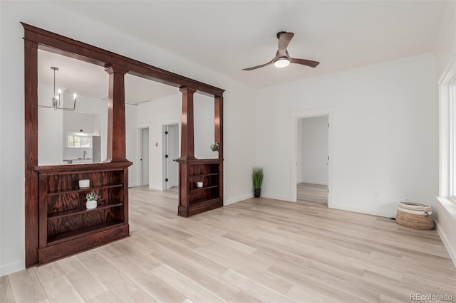 unfurnished room with ceiling fan with notable chandelier and light hardwood / wood-style floors