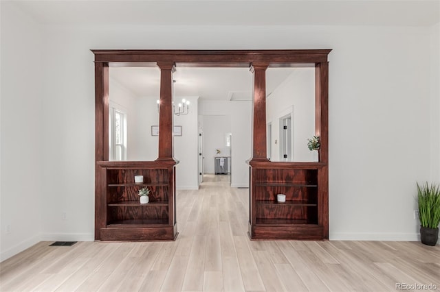 corridor featuring light hardwood / wood-style floors and an inviting chandelier