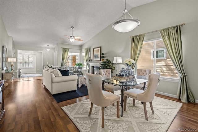 dining area featuring vaulted ceiling, a textured ceiling, ceiling fan, wood finished floors, and baseboards