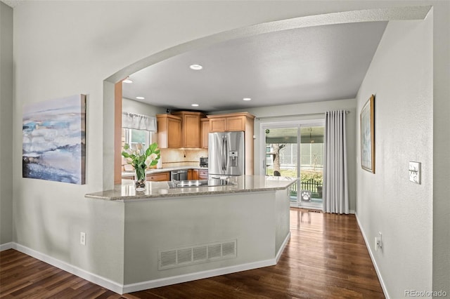 kitchen featuring stainless steel fridge with ice dispenser, arched walkways, dark wood-style flooring, plenty of natural light, and recessed lighting