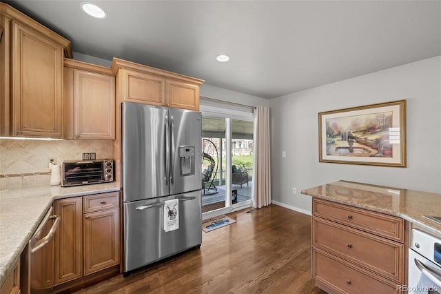 kitchen featuring appliances with stainless steel finishes, tasteful backsplash, dark wood finished floors, light stone counters, and baseboards