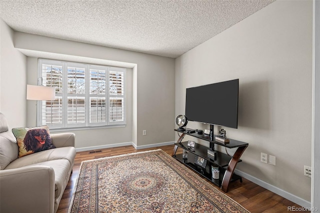 living room featuring wood finished floors, baseboards, and a textured ceiling