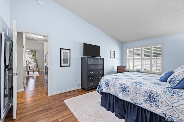 bedroom with lofted ceiling, wood finished floors, and baseboards