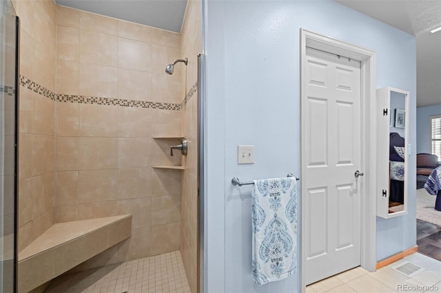 ensuite bathroom with tiled shower and tile patterned floors