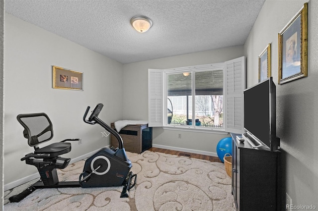 workout area featuring wood finished floors, baseboards, and a textured ceiling