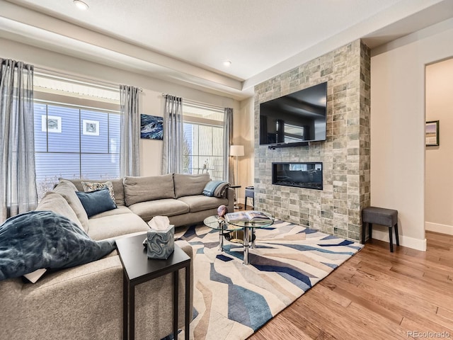 living room with recessed lighting, a large fireplace, baseboards, and wood finished floors