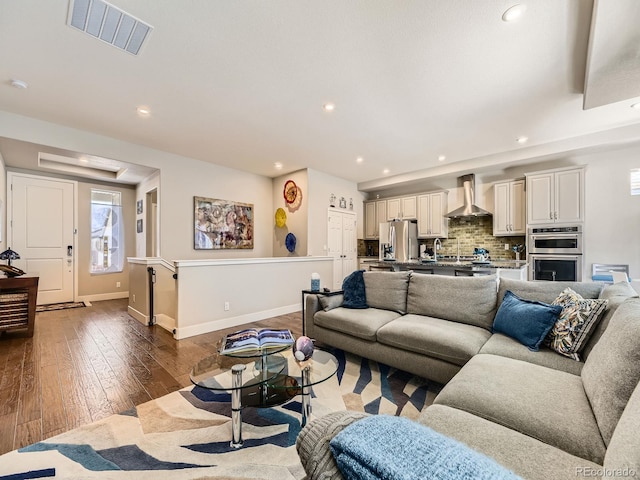 living area with baseboards, visible vents, dark wood-style flooring, and recessed lighting