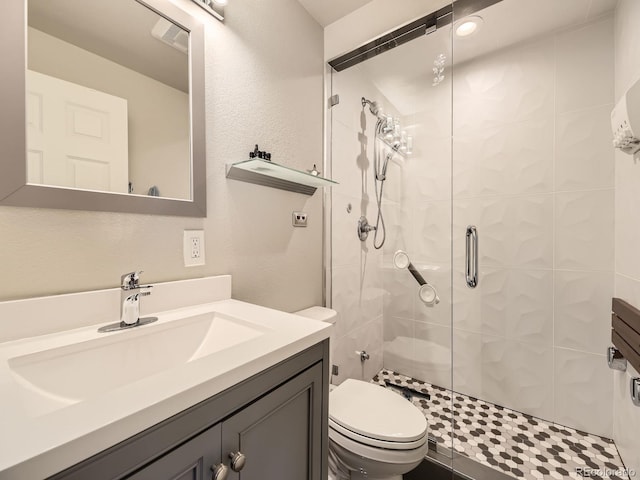 full bath featuring a stall shower, visible vents, a textured wall, toilet, and vanity