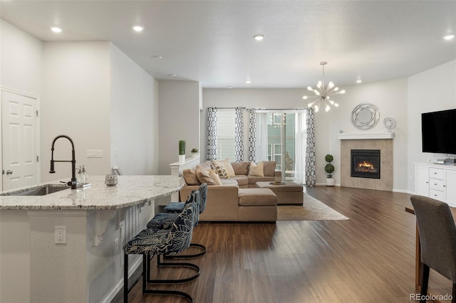 living room featuring a chandelier, recessed lighting, a fireplace, baseboards, and dark wood-style floors