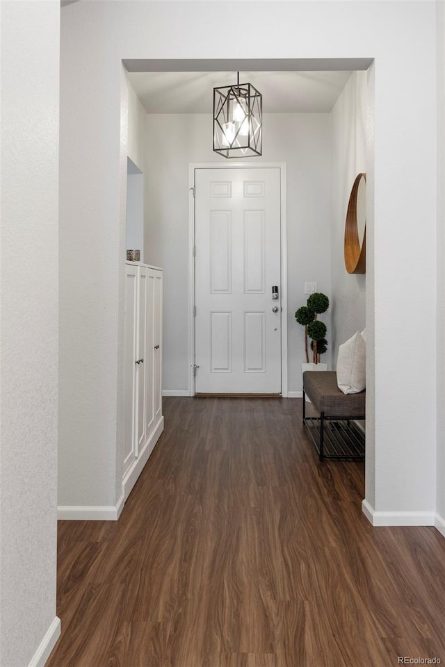 interior space with a chandelier, dark wood finished floors, and baseboards