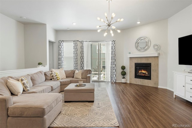 living room featuring recessed lighting, wood finished floors, baseboards, a tiled fireplace, and an inviting chandelier