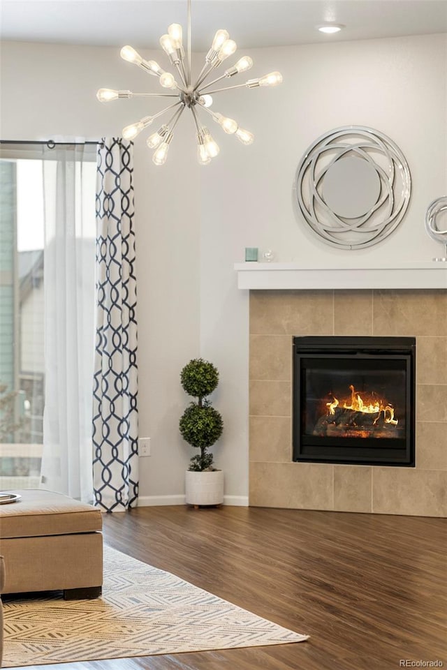 unfurnished living room featuring baseboards, a fireplace, a chandelier, and wood finished floors