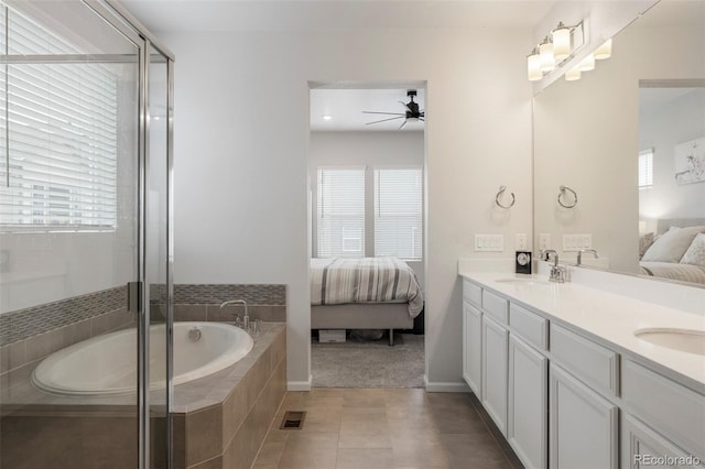 bathroom featuring double vanity, a healthy amount of sunlight, connected bathroom, a sink, and a bath