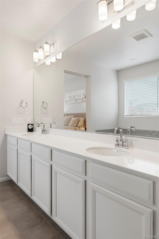 ensuite bathroom featuring double vanity, a sink, and visible vents