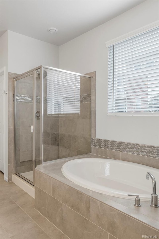 bathroom featuring tile patterned flooring, a garden tub, and a shower stall