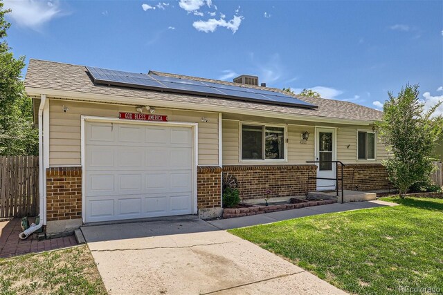 single story home featuring a garage, a front yard, and solar panels