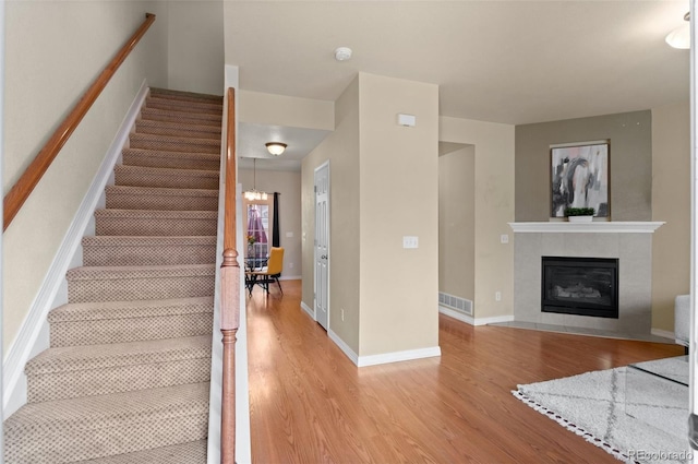 stairway with baseboards, a fireplace, visible vents, and wood finished floors