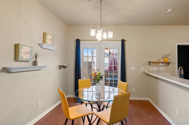 dining area with a chandelier, wood finished floors, and baseboards